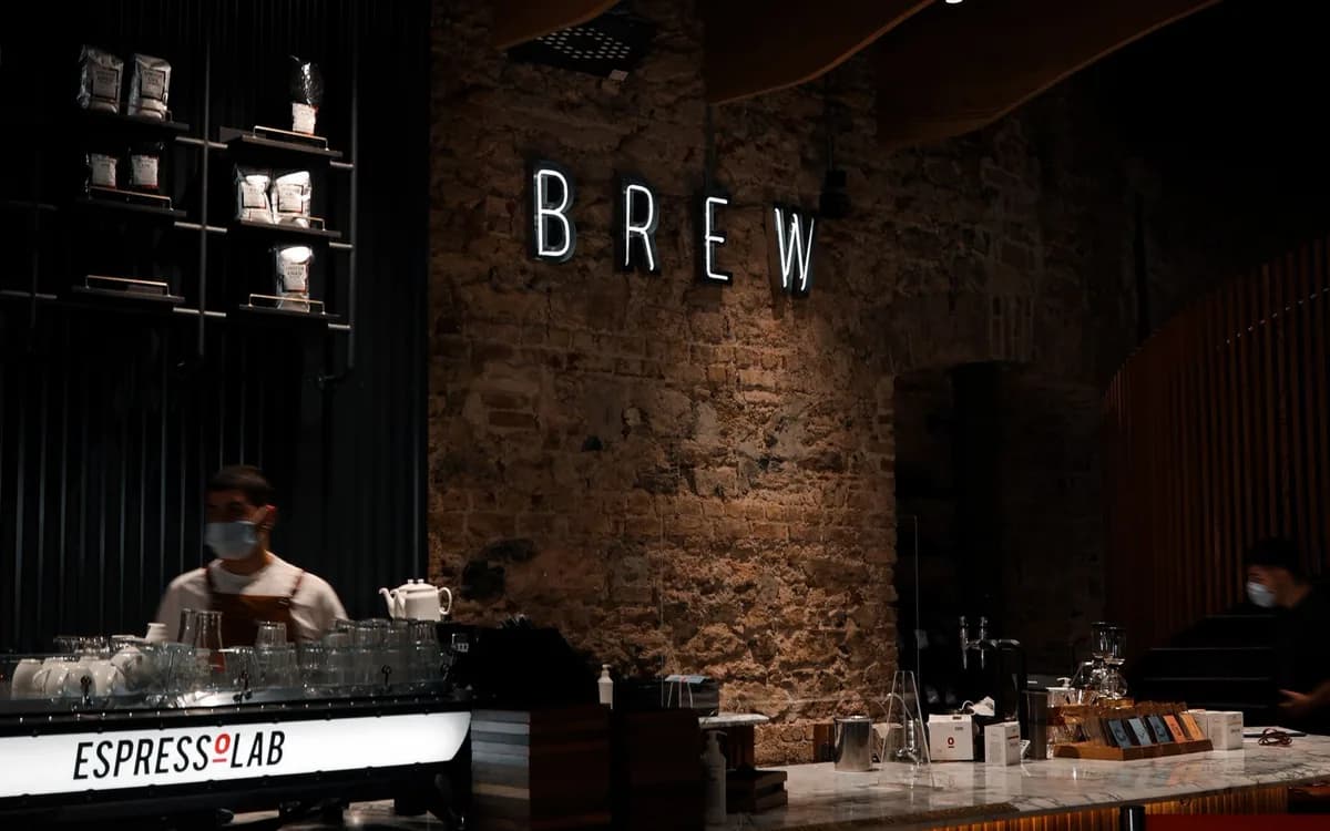 Un barista derrière le comptoir d’un café, près du matériel de préparation.
