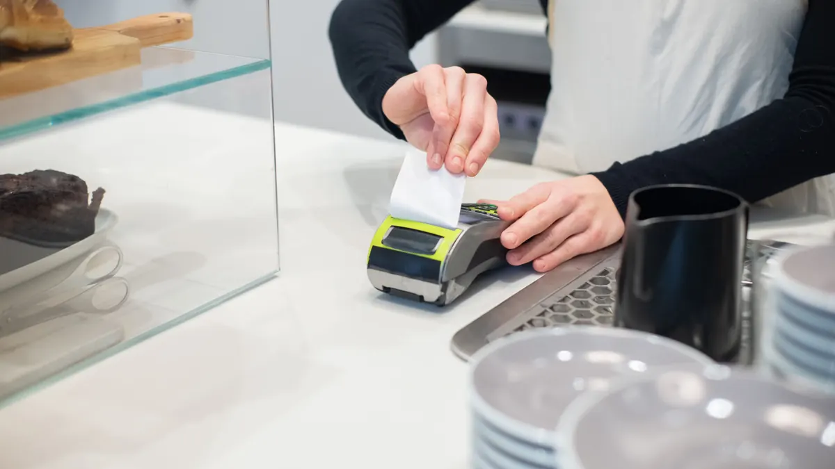 Cafe employee printing a card-payment receipt at the point-of-sale terminal