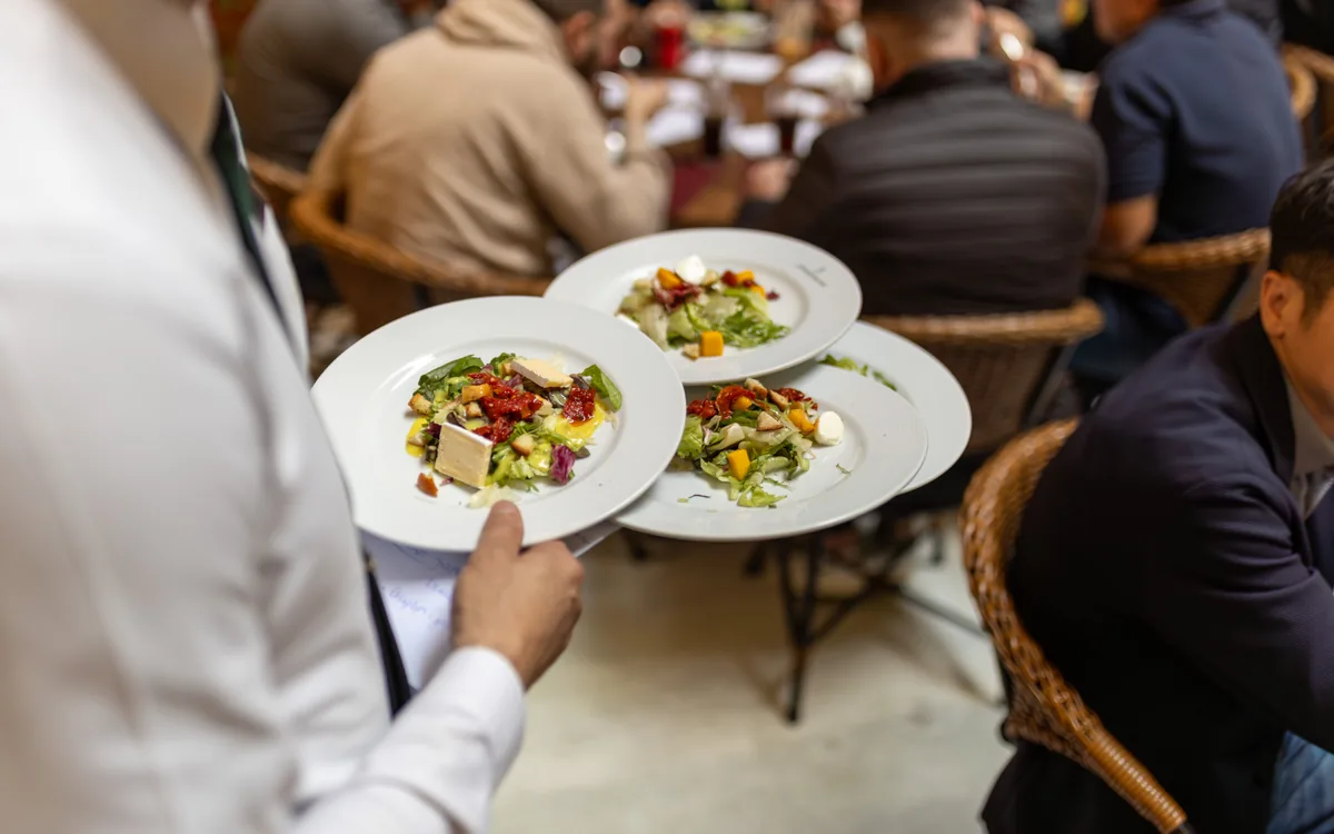 Serveur transportant trois assiettes dans un restaurant.