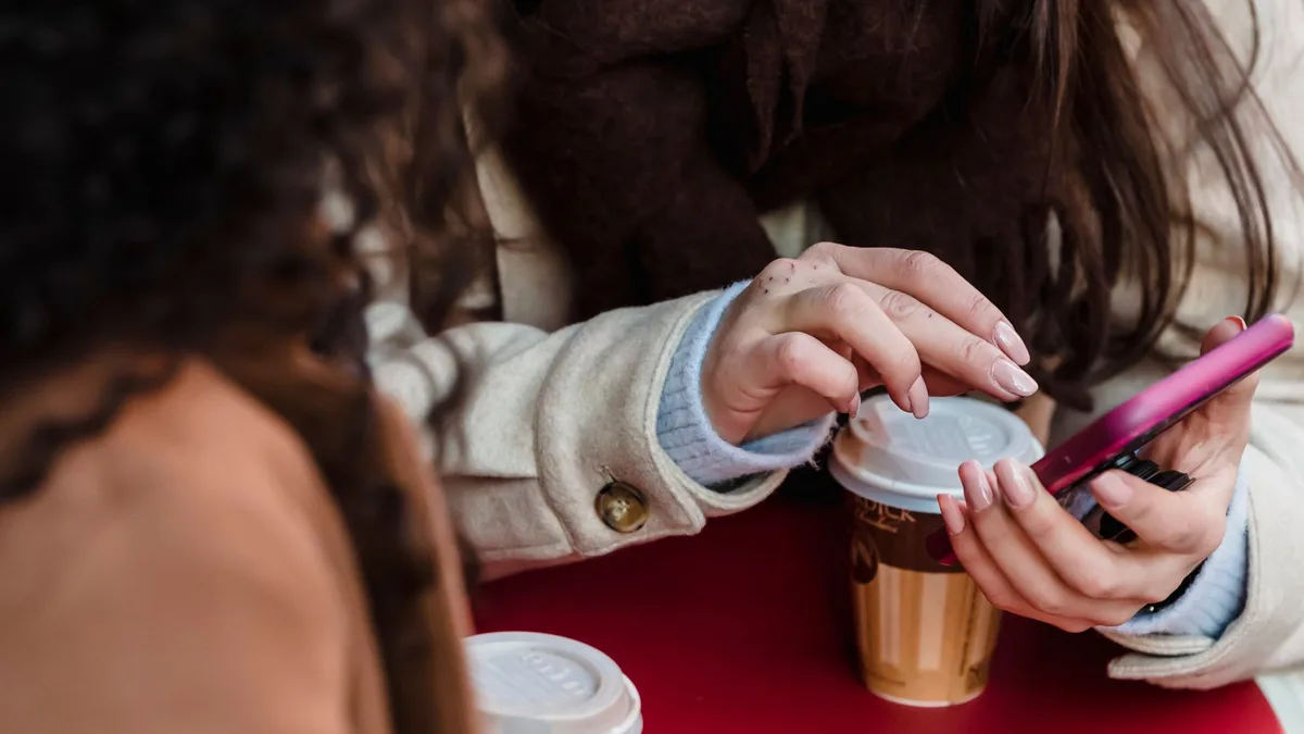 People reviewing holiday plans on a phone at an outdoor cafe table