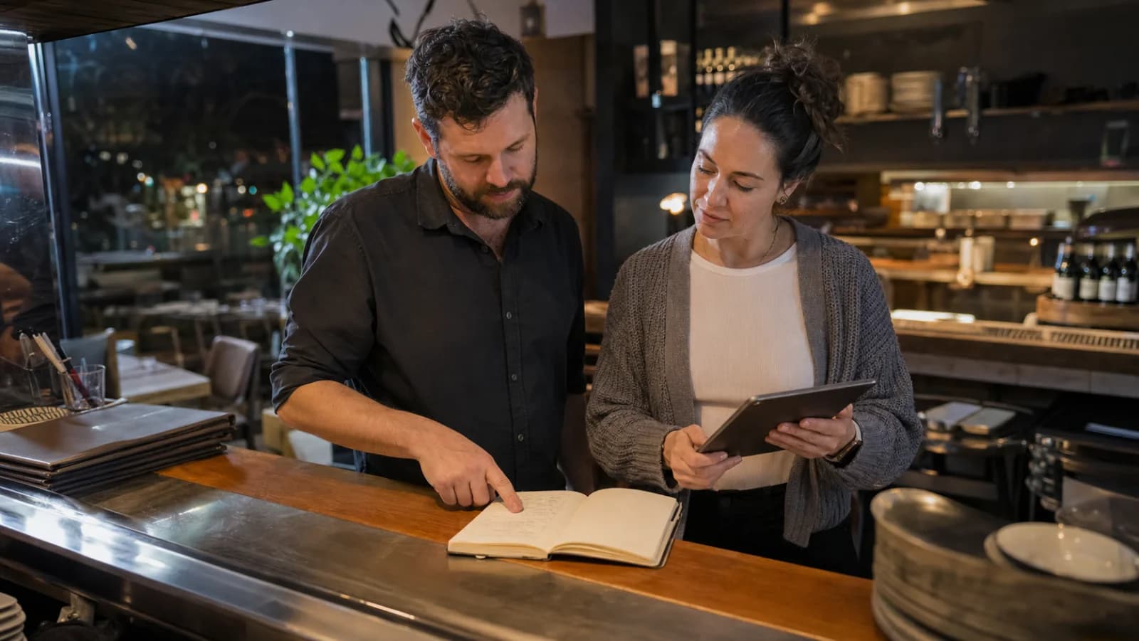 Deux gestionnaires de restaurant examinent une note de passation posée à plat après le service