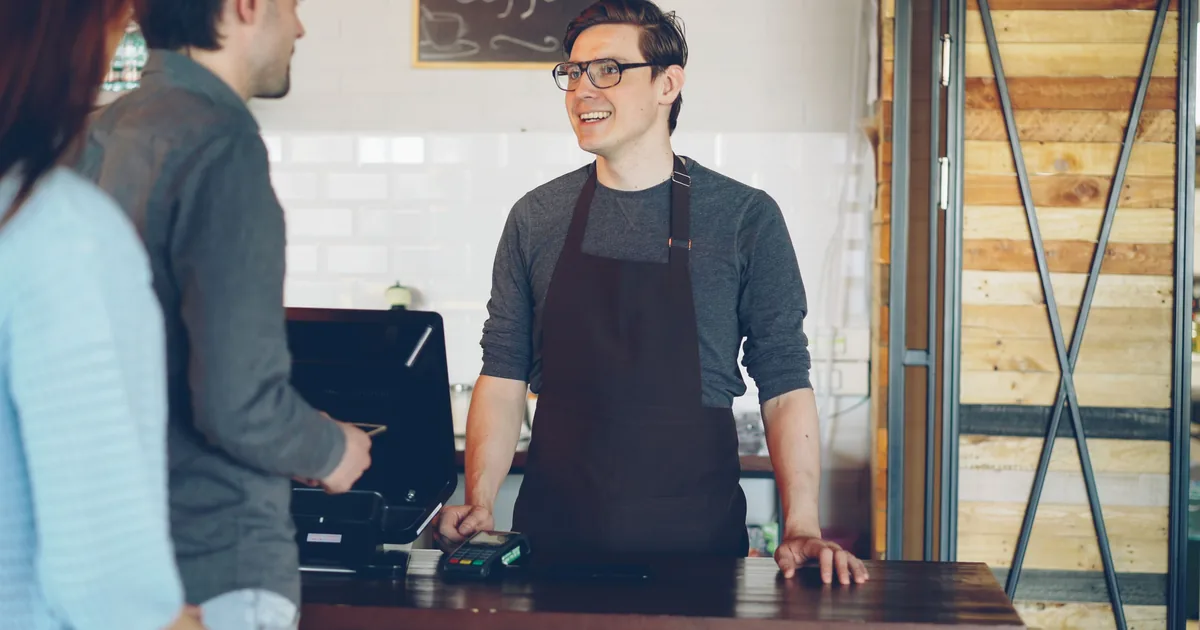 A café barista talking with customers across the service counter.