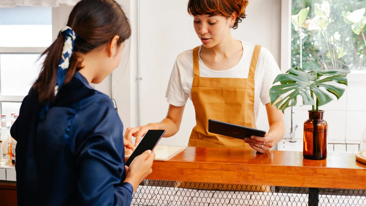 Cafe employees reviewing a tablet during a shift handoff