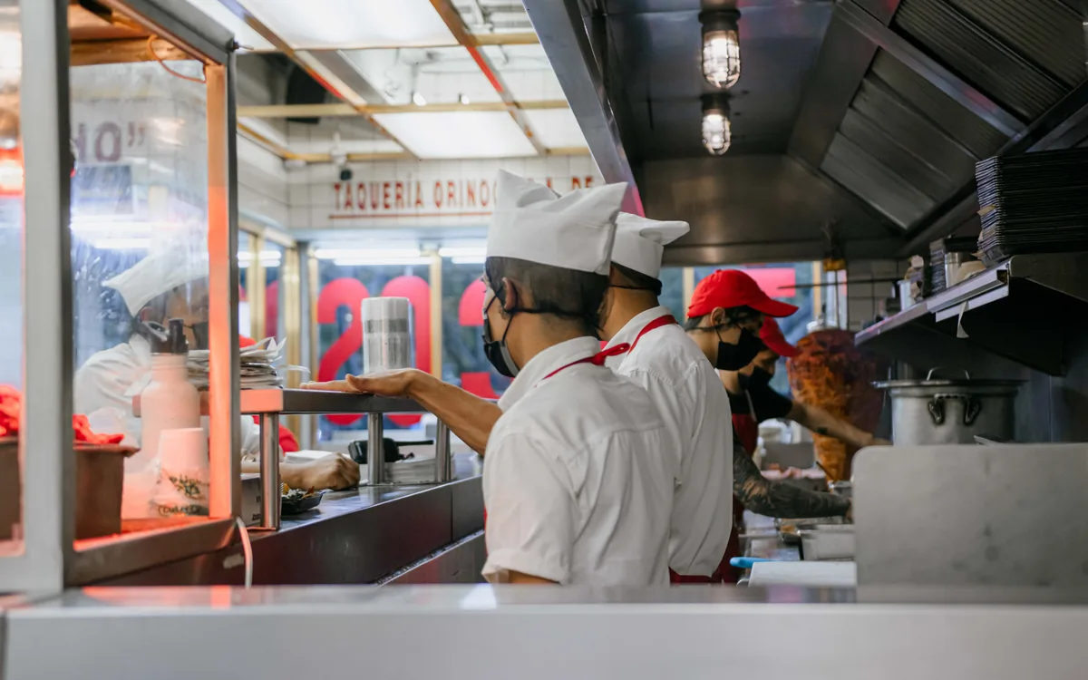 Restaurant kitchen staff preparing food behind a service counter.